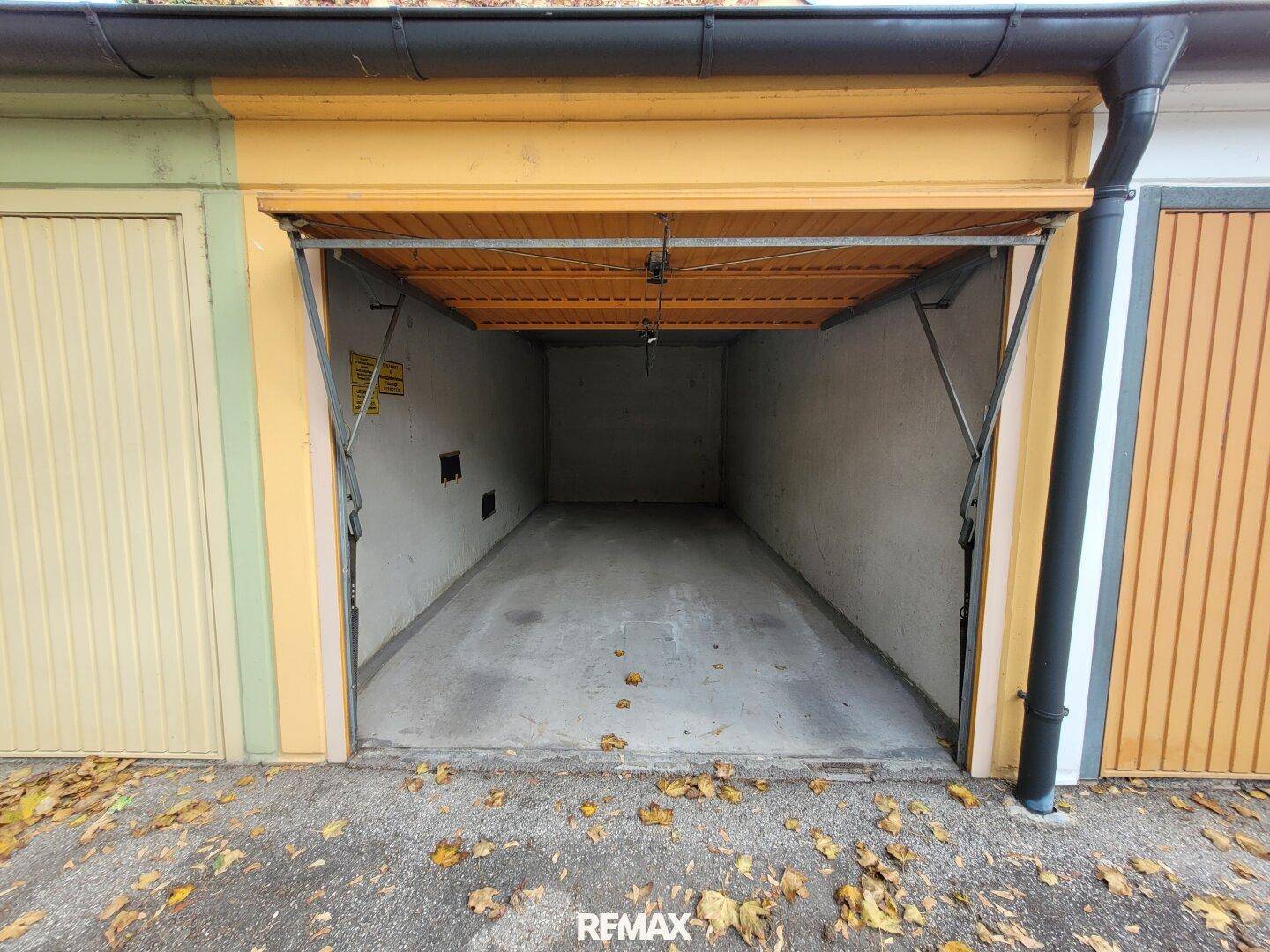 Einzelgarage mit geöffnetem Tor und Betonboden, umgeben von anderen Garagen.