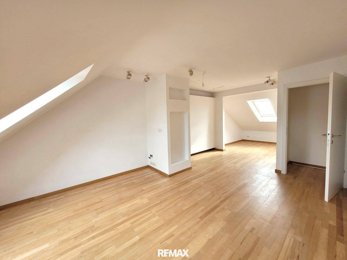 Geräumiger Dachbodenraum mit Holzboden und Dachfenster, ideal für ein Schlafzimmer oder Büro.