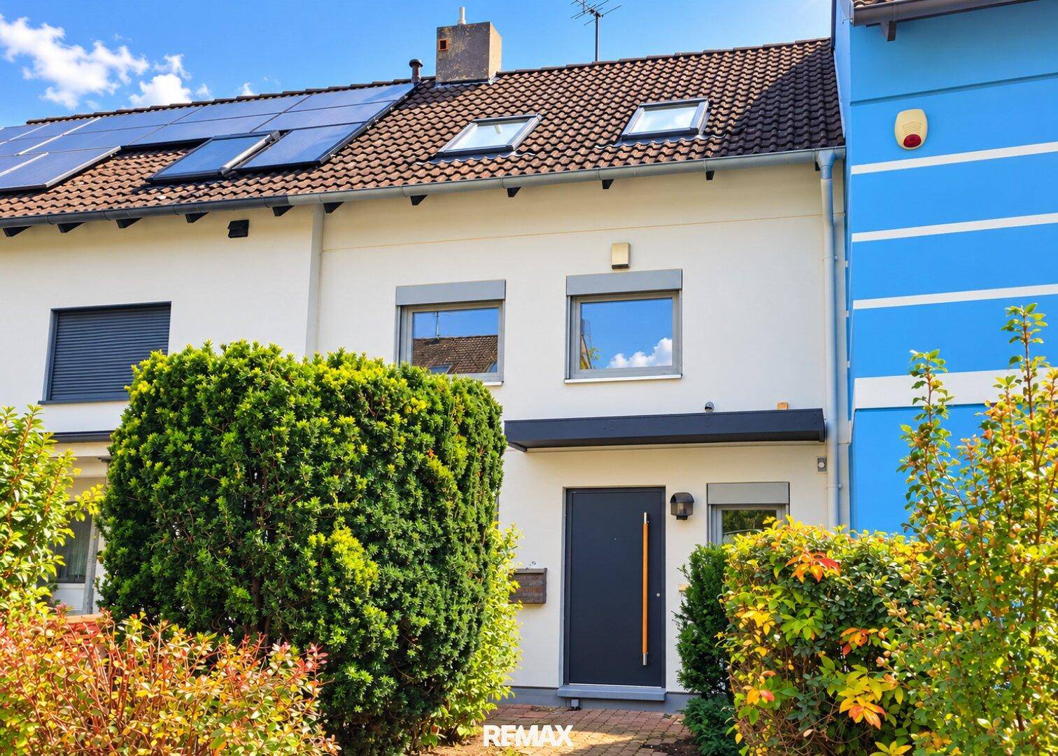 Vorderansicht eines Reihenhauses mit Solaranlage auf dem Dach und gepflegtem Vorgarten.