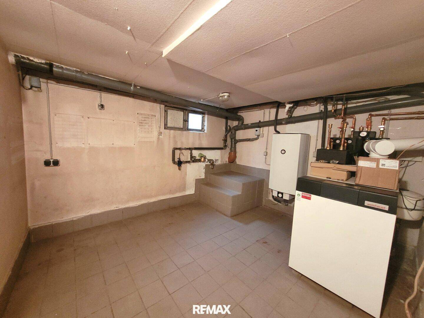 Heizraum im Keller mit Heizungsanlage und sichtbaren Rohren.
