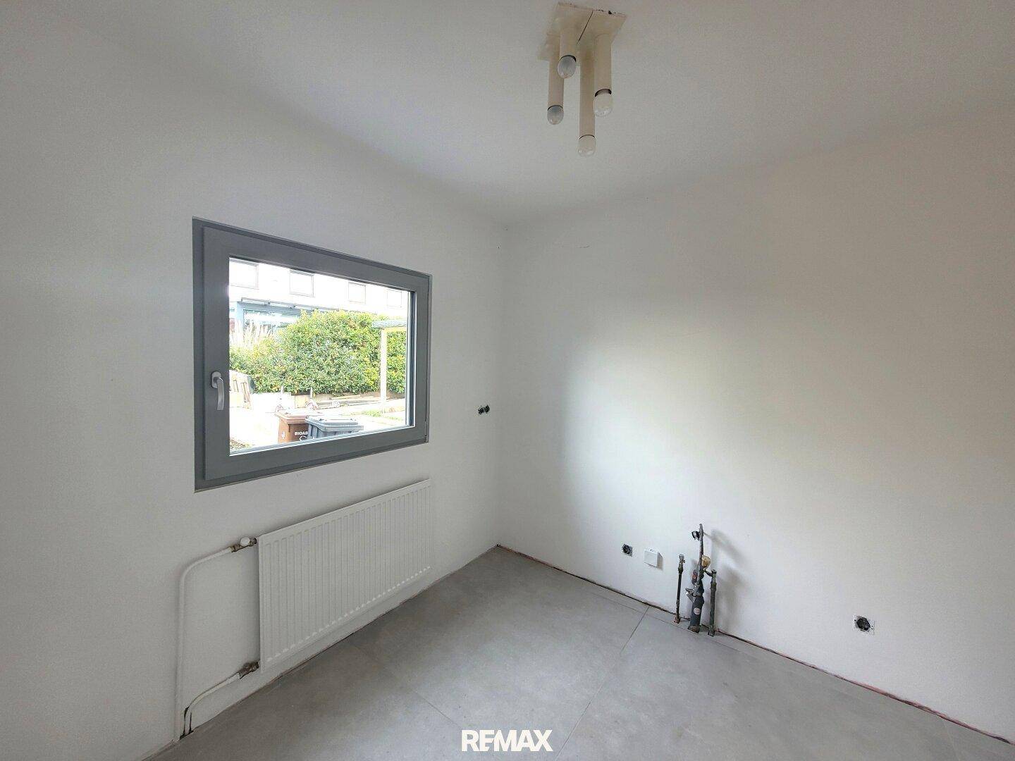 Leerer Raum mit einem Fenster und Heizkörper, bereit für individuelle Gestaltungsmöglichkeiten.