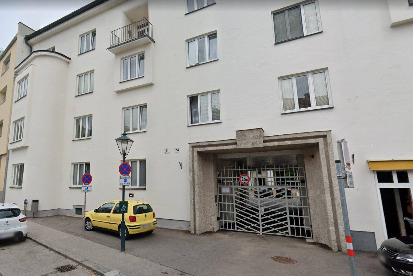 Straßenansicht eines Wohnhauses mit Garageneinfahrt und Balkon im oberen Stockwerk.
