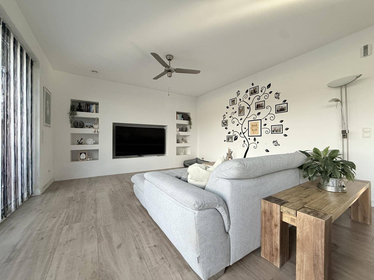 Wohnzimmer mit großem Fernseher, Sofa und dekorativer Wandgestaltung.