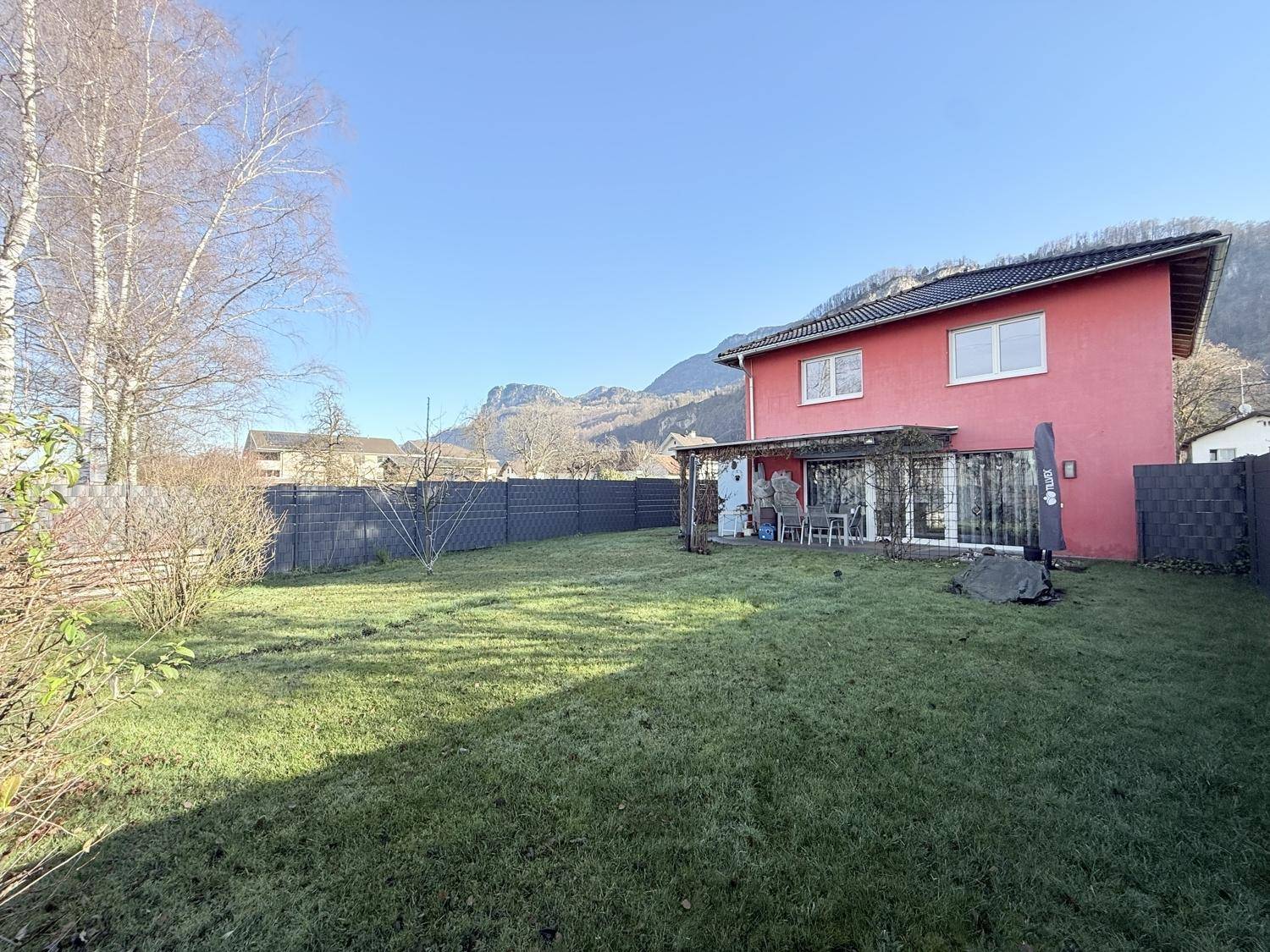 Gepflegter Garten mit Rasenfläche und Blick auf die umliegenden Berge.