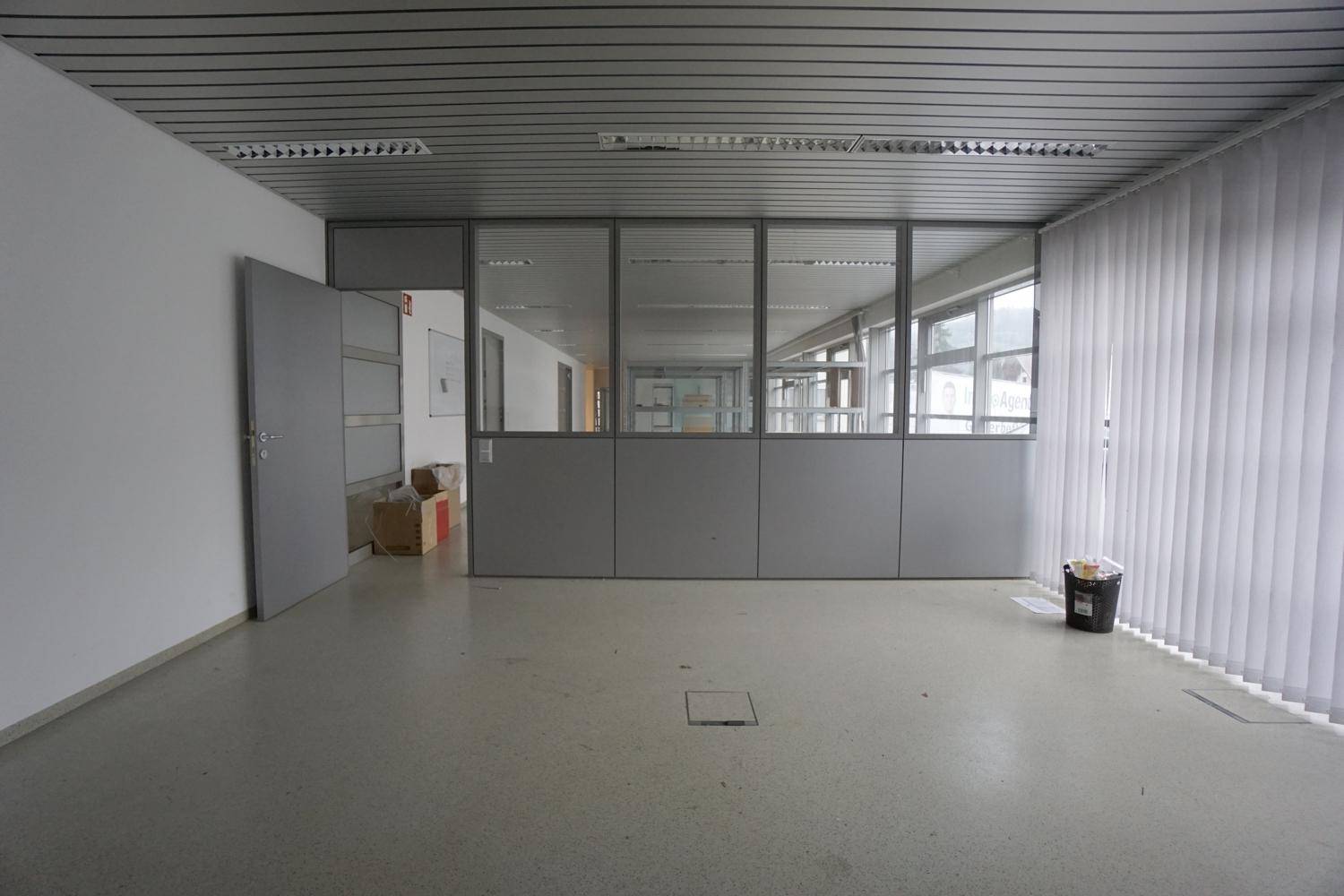 Bürofläche mit Glasabtrennungen, die den Raum unterteilen, und einer modernen Deckenverkleidung.