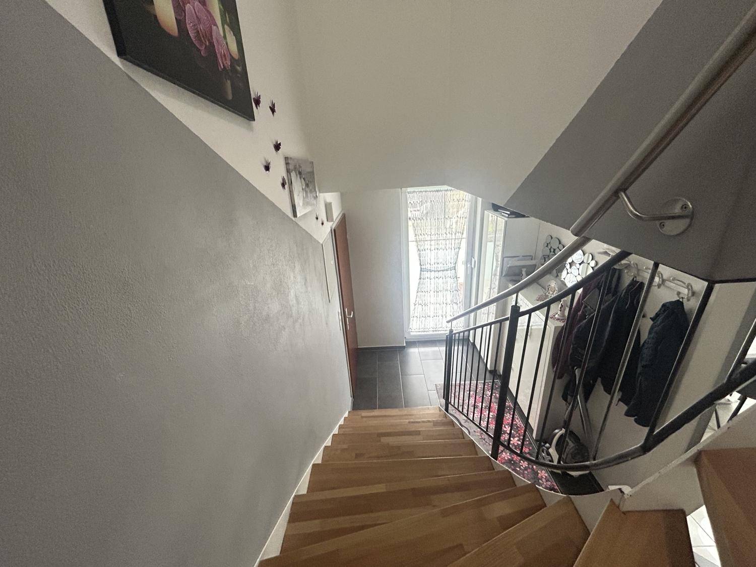 Treppenhaus mit Holzstufen und modernem Geländer, das die verschiedenen Ebenen des Hauses verbindet.