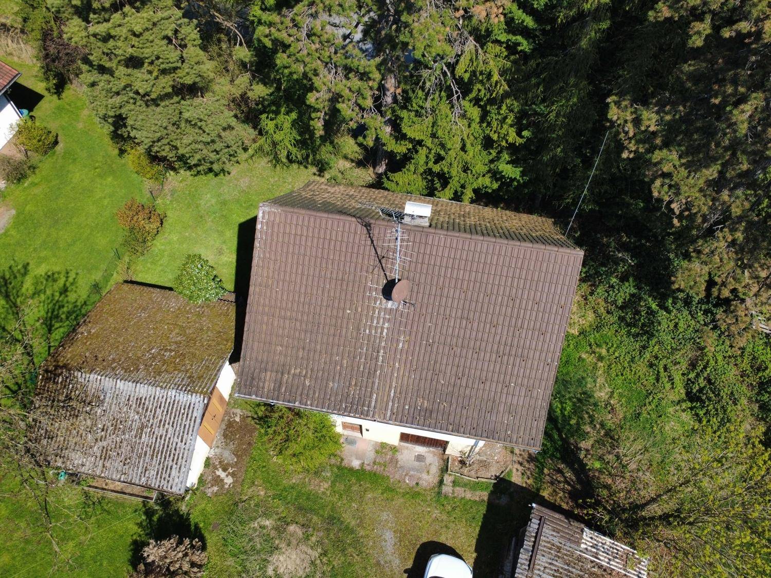 Detaillierte Luftaufnahme des Daches mit Antenne und umgebenden Bäumen.