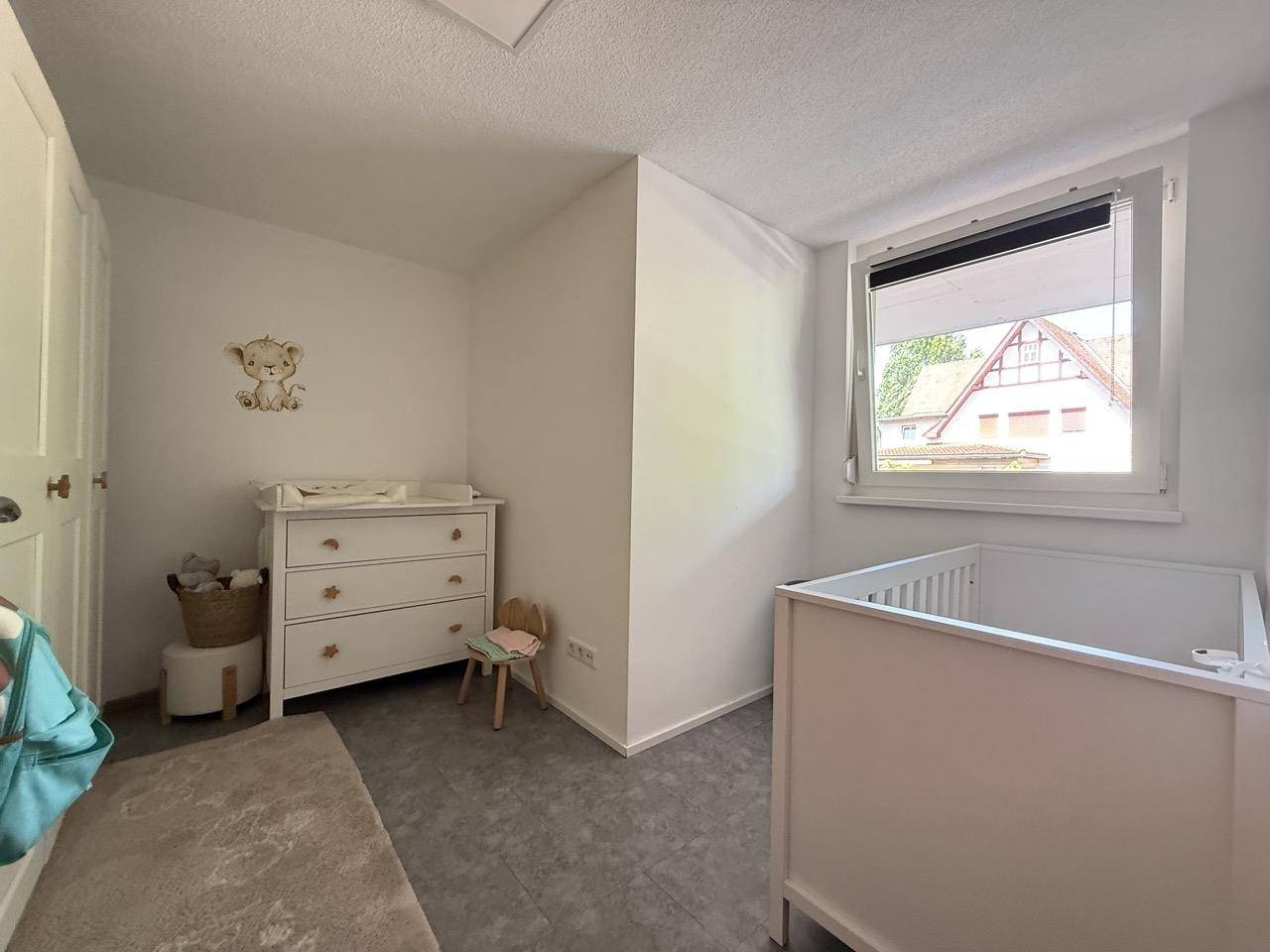 Kinderzimmer mit Wickeltisch, Babybett und hellem Fenster.