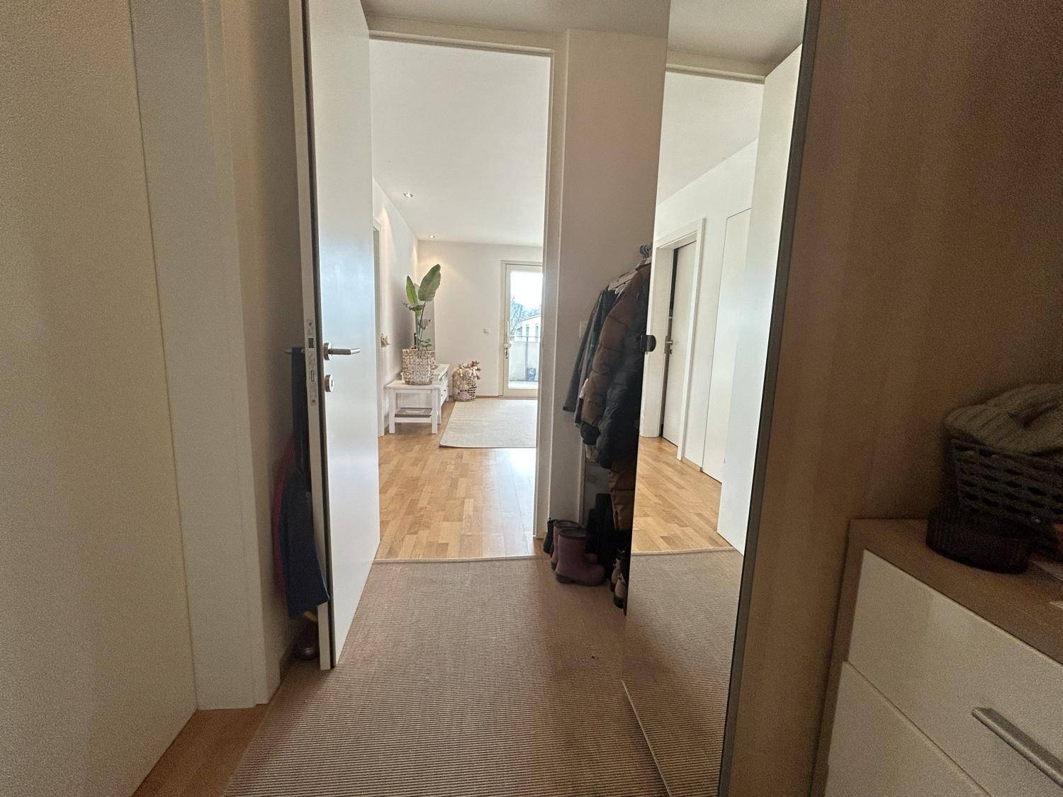 Heller Flur mit Garderobe und großem Spiegel, der zu den Wohnbereichen führt.