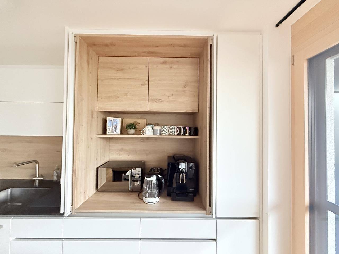 Praktischer Küchenschrank mit integrierter Mikrowelle, Kaffeemaschine und Wasserkocher.