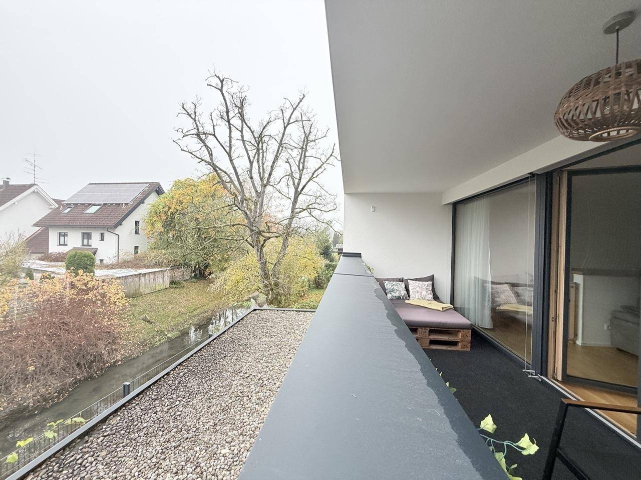 Balkon mit Blick auf einen Bachlauf und Bäume, bietet eine ruhige Aussicht.