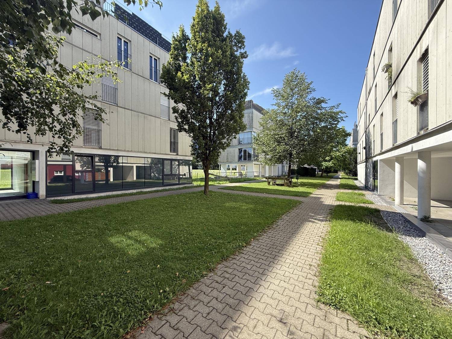 Weitläufiger Innenhof der Wohnanlage mit gepflegten Grünflächen und Sitzgelegenheiten im Freien.