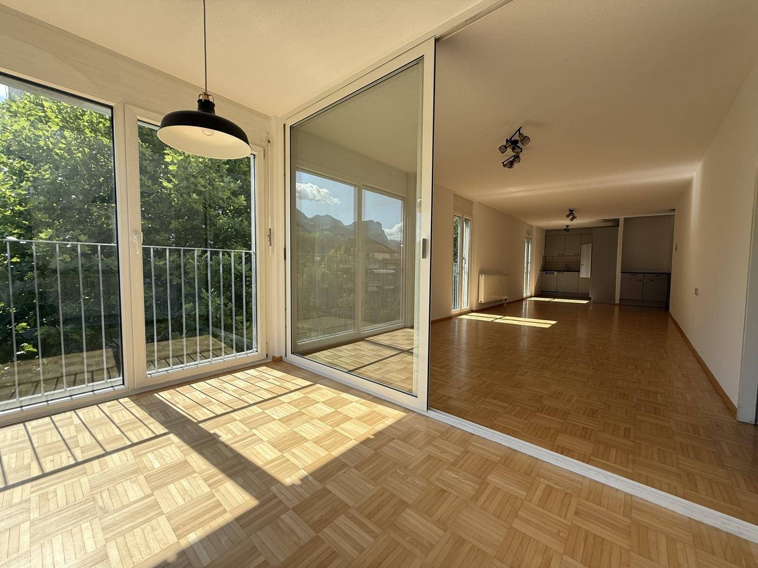 Blick von der Loggia in den Wohnbereich mit durchgehendem Parkettboden und viel Helligkeit.