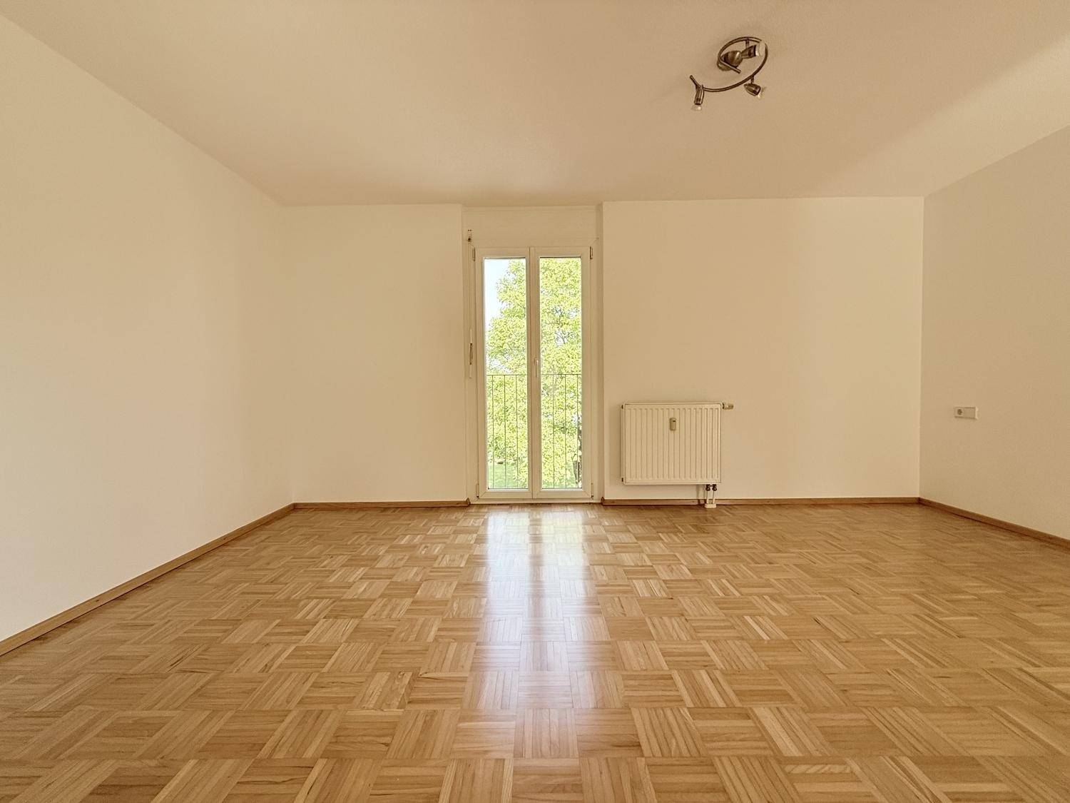 Helles Zimmer mit Parkettboden und einem französischen Balkon, ideal als Schlaf- oder Arbeitszimmer.