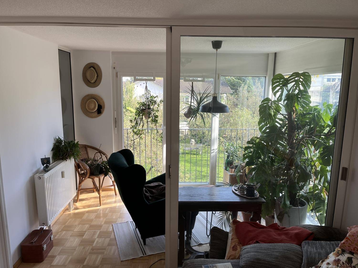 Blick vom Wohnzimmer in die möblierte Loggia mit Pflanzen und viel Tageslicht.