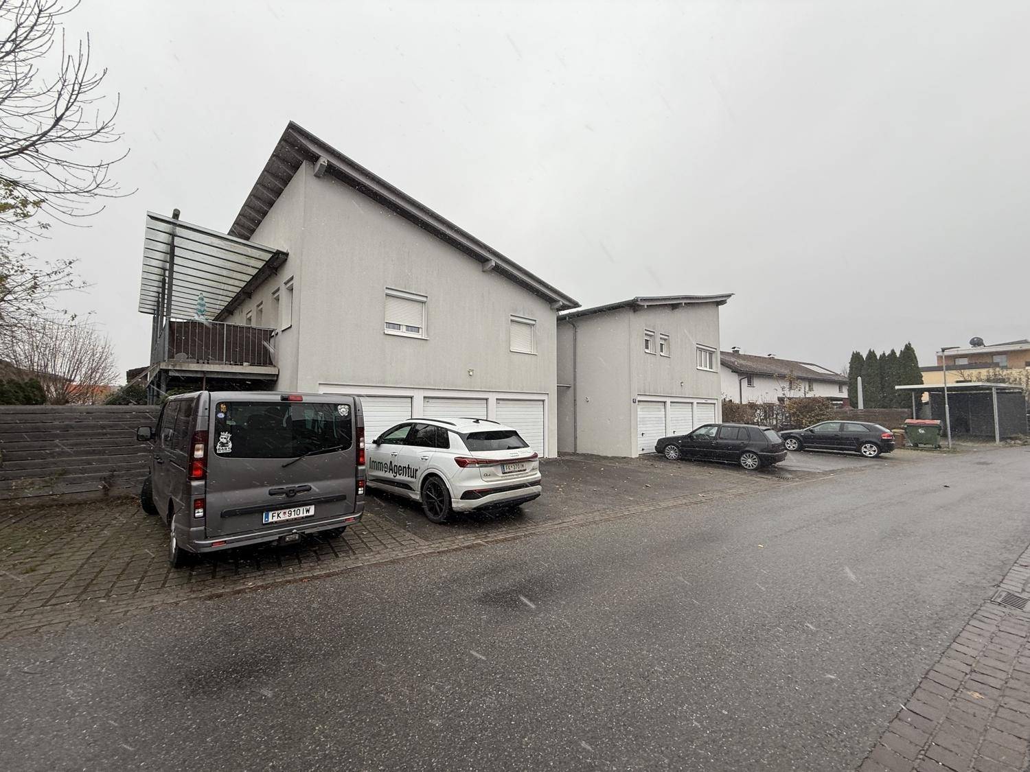 Gebäudefassade mit mehreren Garagen und Stellplätzen an einem bewölkten Tag.