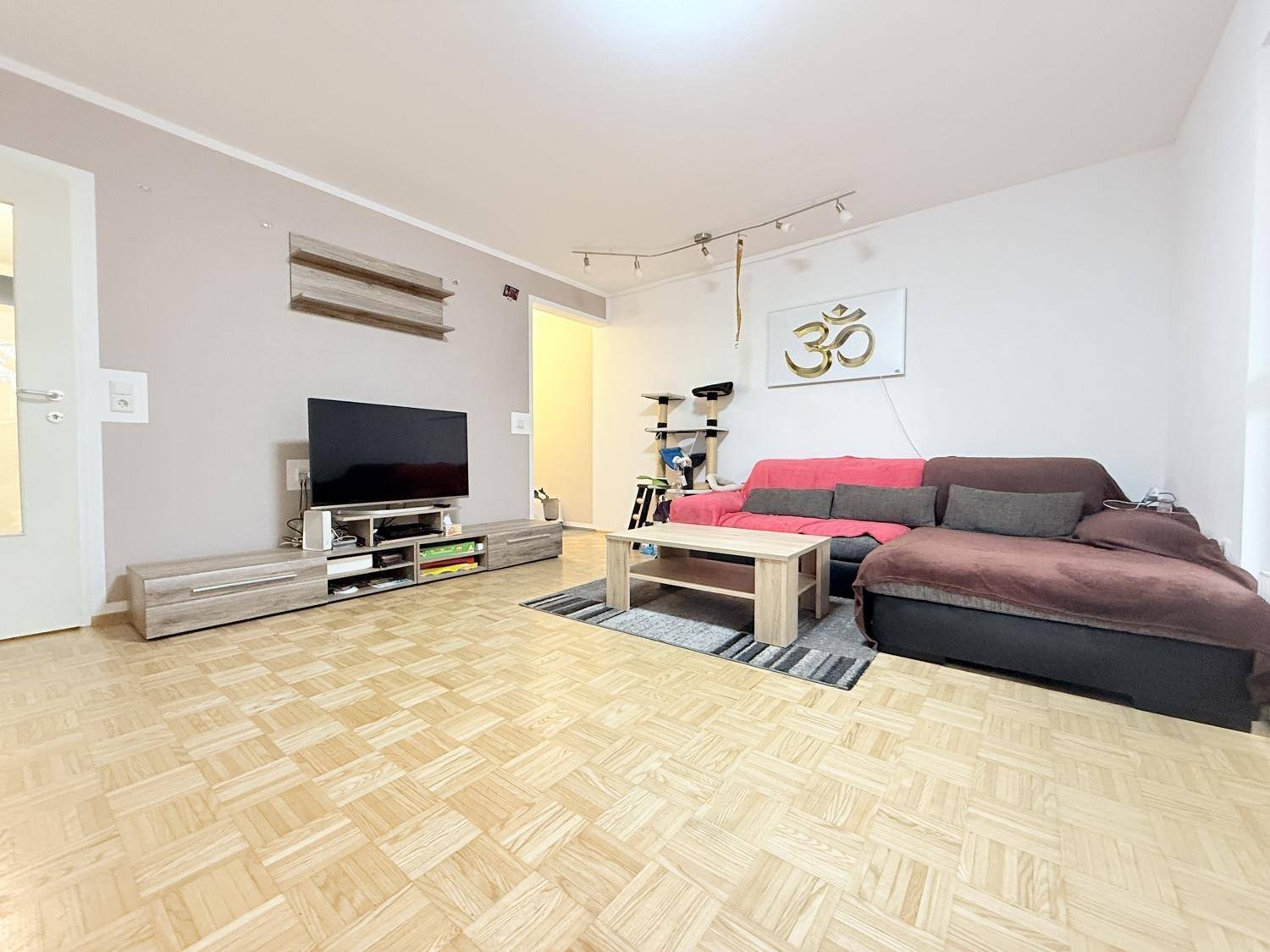 Gemütliches Wohnzimmer mit Parkettboden, bequemer Couch und TV-Möbeln für entspannte Abende.