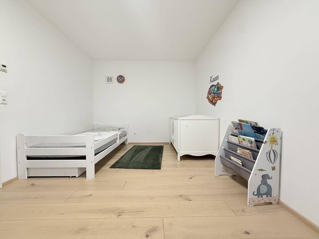 Kinderzimmer mit hellem Holzboden, Einzelbett und Babybett, ideal für Geschwister.
