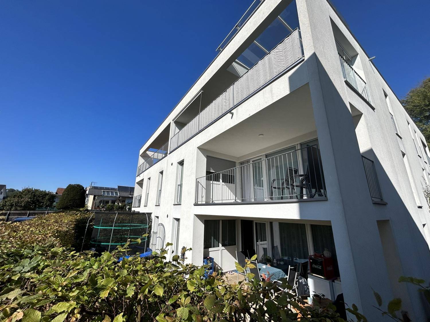 Moderne Architektur eines Mehrfamilienhauses mit mehreren Balkonen unter blauem Himmel.