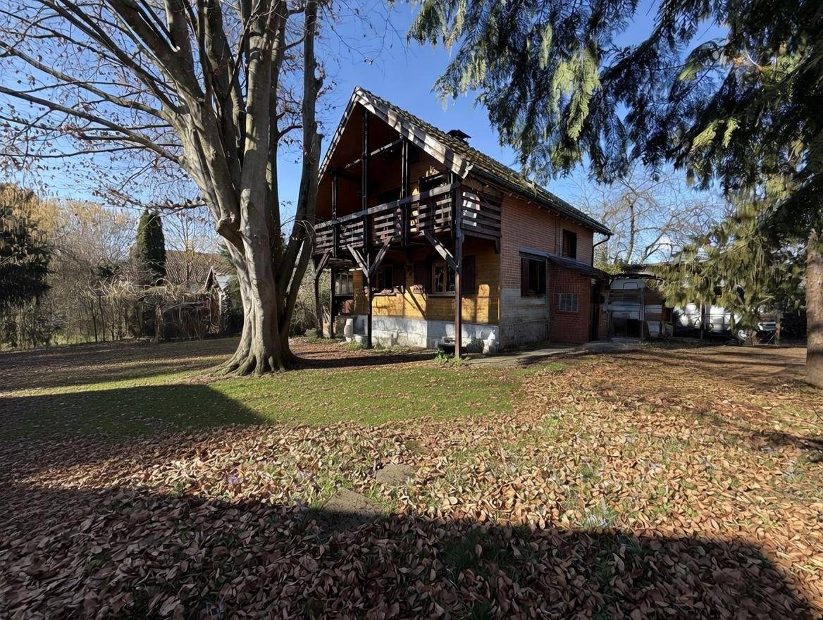 Charmantes Holzhaus mit traditioneller Architektur und weitläufigem Gartenbereich unter blauem Himmel.
