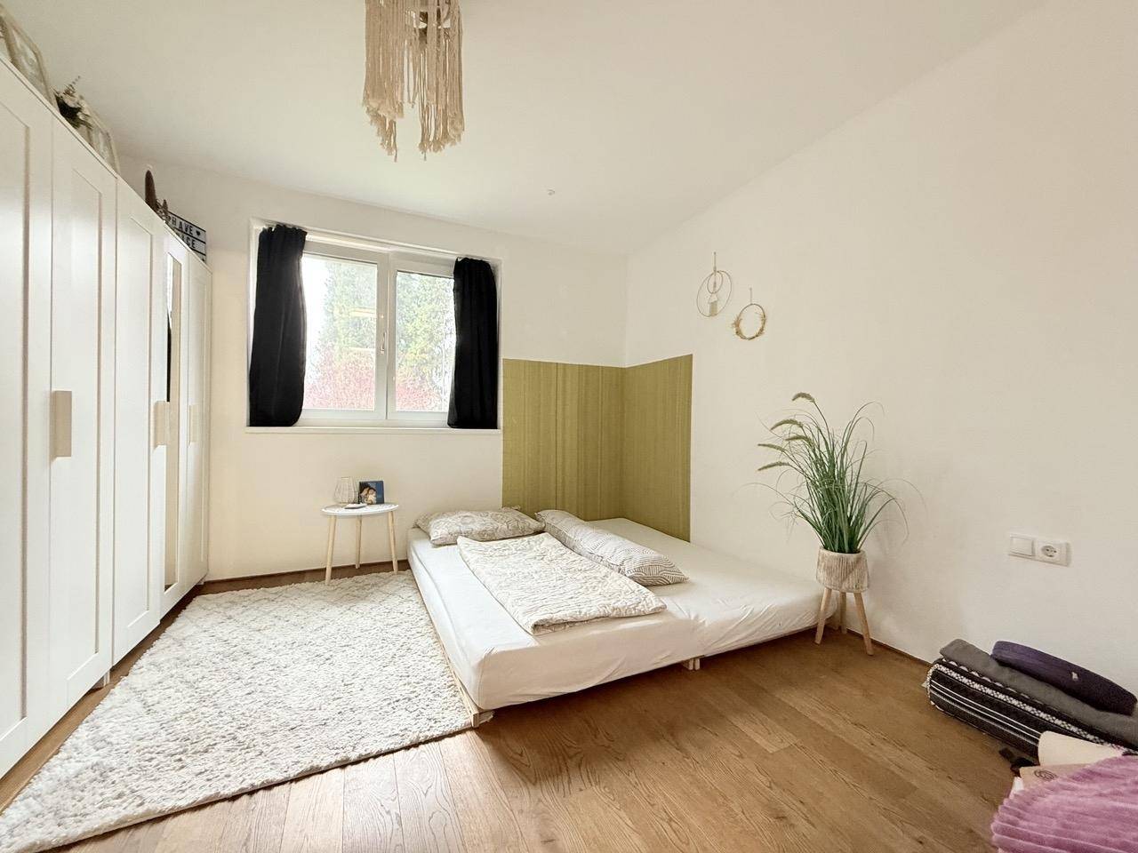 Helles Schlafzimmer mit Holzboden, Kleiderschrank und gemütlicher Atmosphäre.