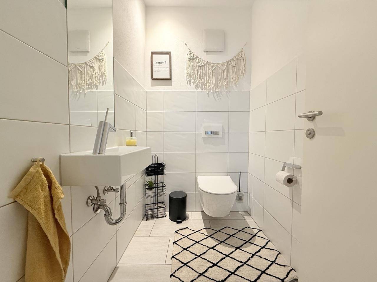 Modernes Gäste-WC mit Wand-WC, kleinem Waschbecken und stilvoller Dekoration.