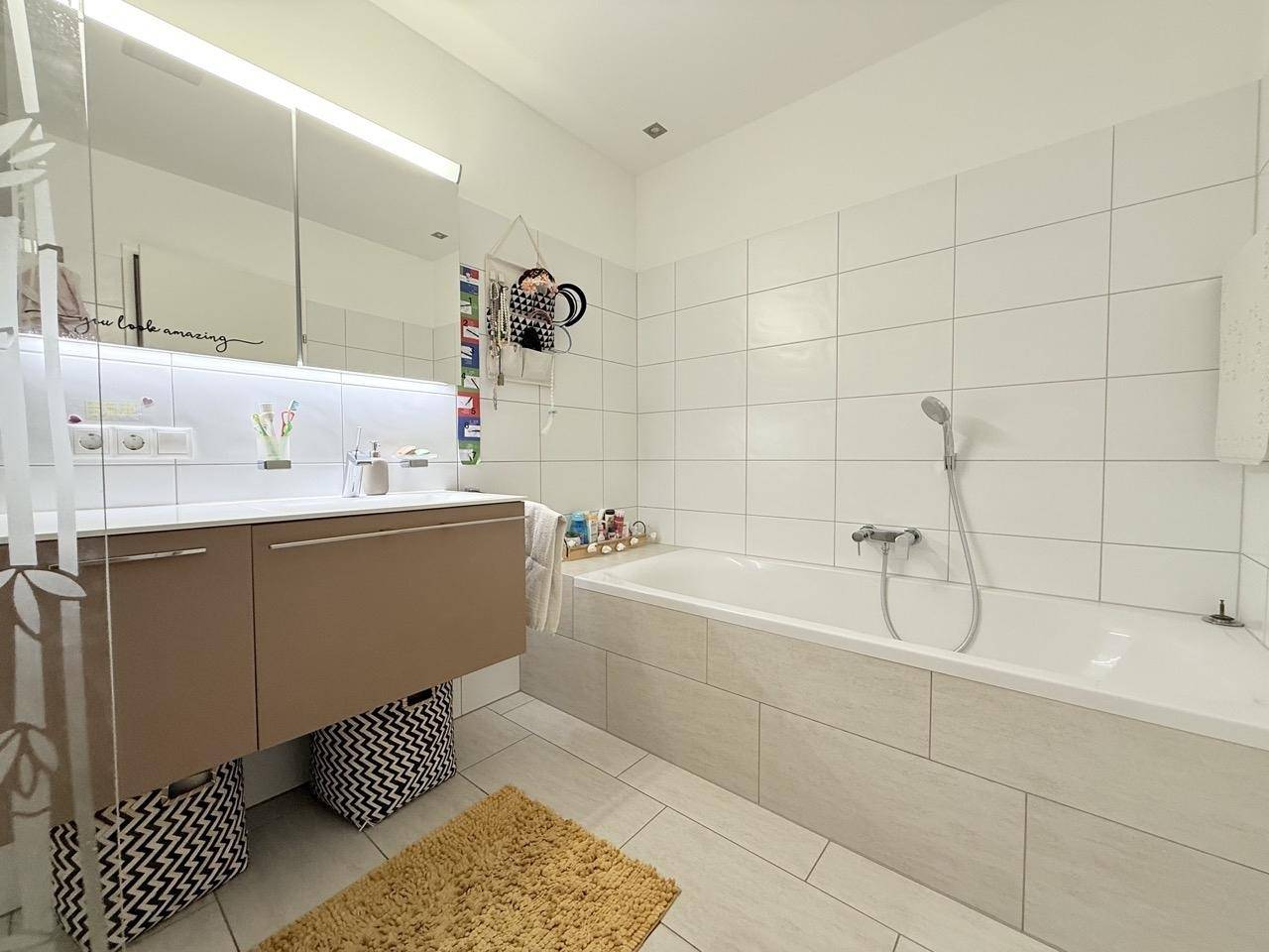 Geräumiges Badezimmer mit Badewanne, modernem Waschtisch und Spiegelschrank.