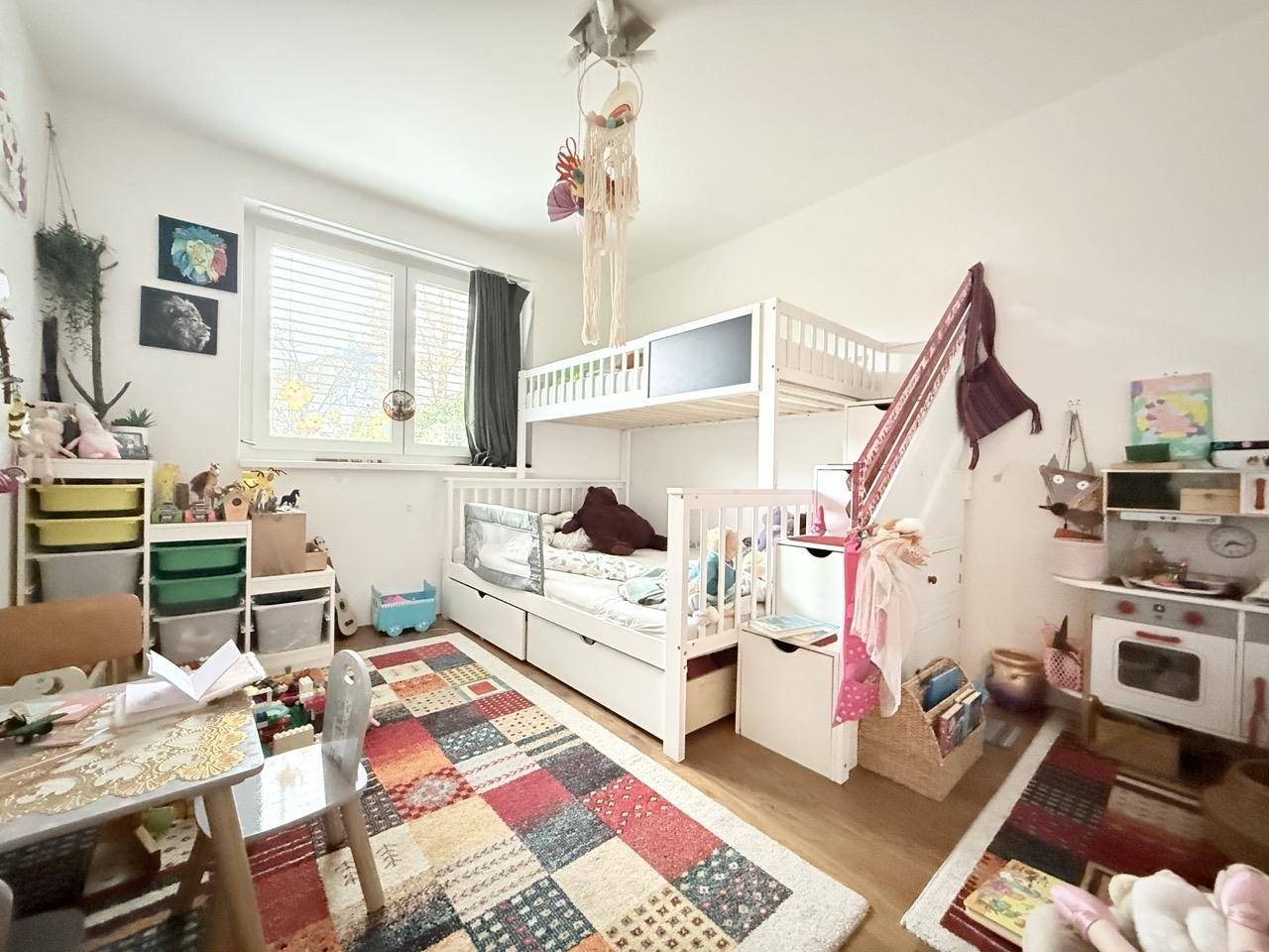 Kinderzimmer mit Etagenbett, Spielbereich und großem Fenster für viel Tageslicht.