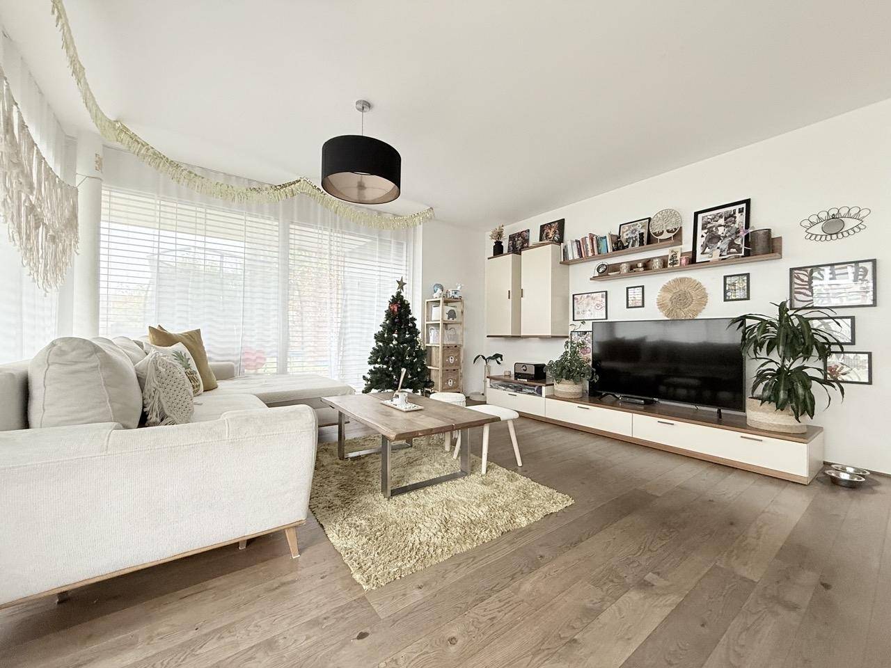Gemütliches Wohnzimmer mit Holzboden, großem Sofa und dekorativer Wandgestaltung.