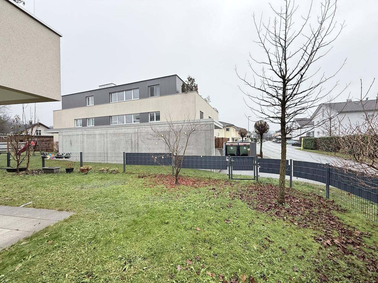 Gepflegter Gartenbereich mit Rasen und Blick auf die moderne Wohnanlage.