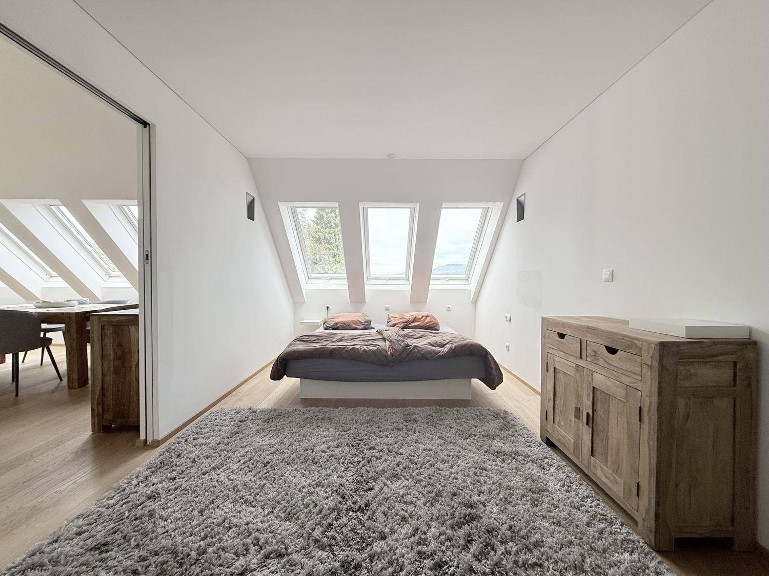 Geräumiges Schlafzimmer mit Doppelbett, Teppich und drei Dachfenstern für helle Atmosphäre.