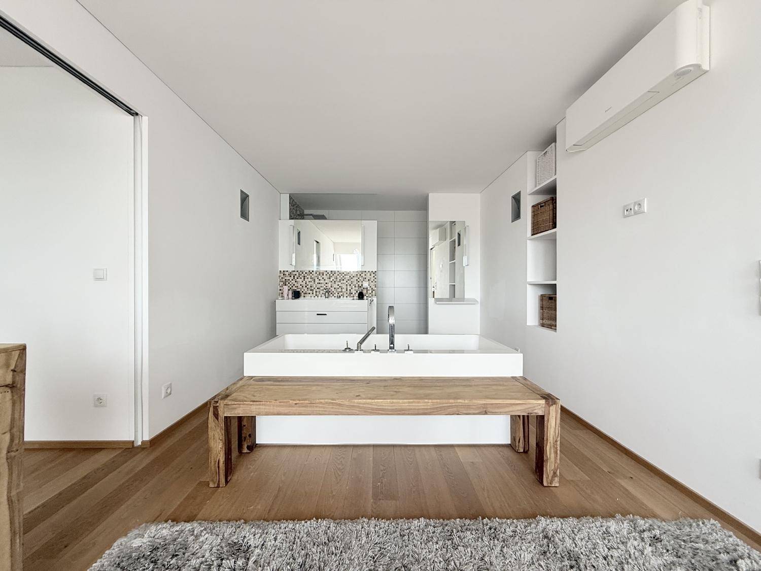 Modernes Badezimmer mit integriertem Waschbecken, Holzboden und Klimaanlage.