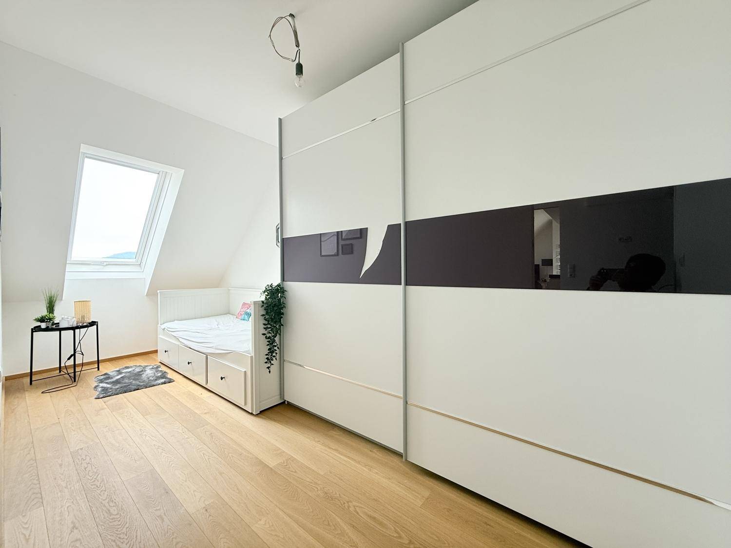 Gemütliches Schlafzimmer mit Holzboden, großem Schiebeschrank und Dachfenster für viel Licht.