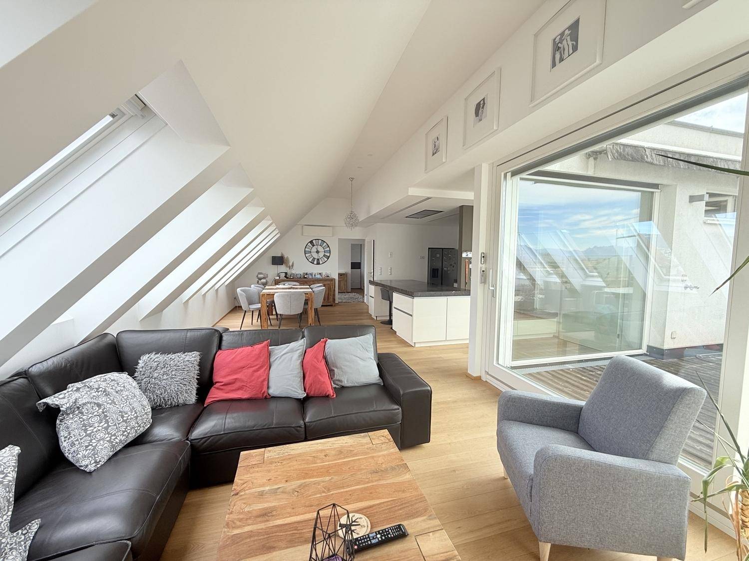 Heller Wohnbereich mit großem Sofa, Holzboden und Zugang zur Terrasse mit Weitblick.