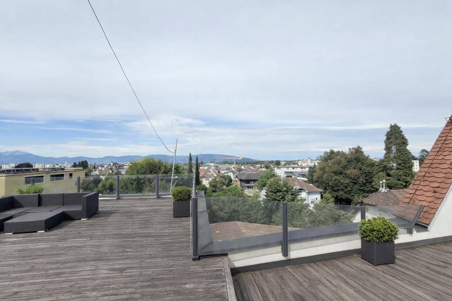 Geräumige Dachterrasse mit Loungemöbeln und weitem Blick über die Stadt und Berge.