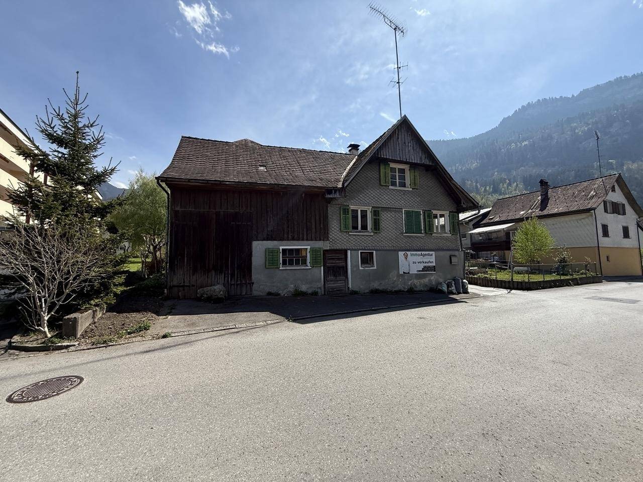 Traditionelles Haus mit Holzfassade und Satteldach, eingebettet in eine Berglandschaft.