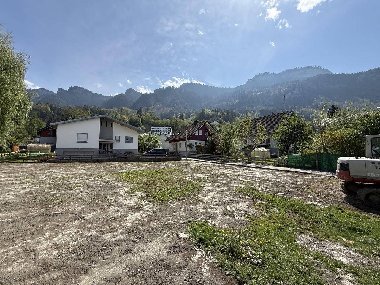 Weitläufiges Grundstück mit Blick auf umliegende Häuser und die beeindruckende Berglandschaft.