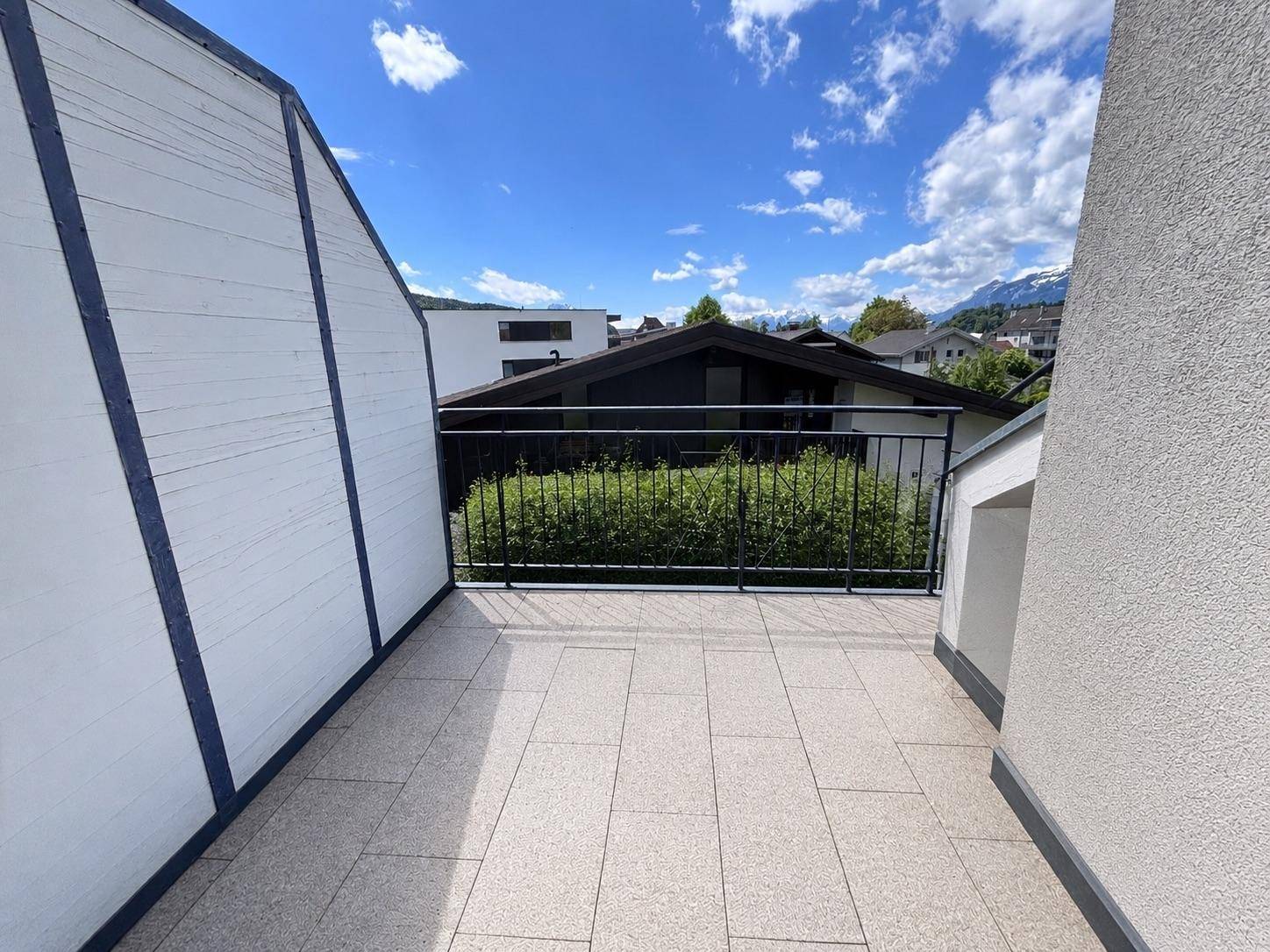 Geräumiger Balkon mit Fliesenboden, Metallgeländer und Blick auf die umliegende Landschaft.