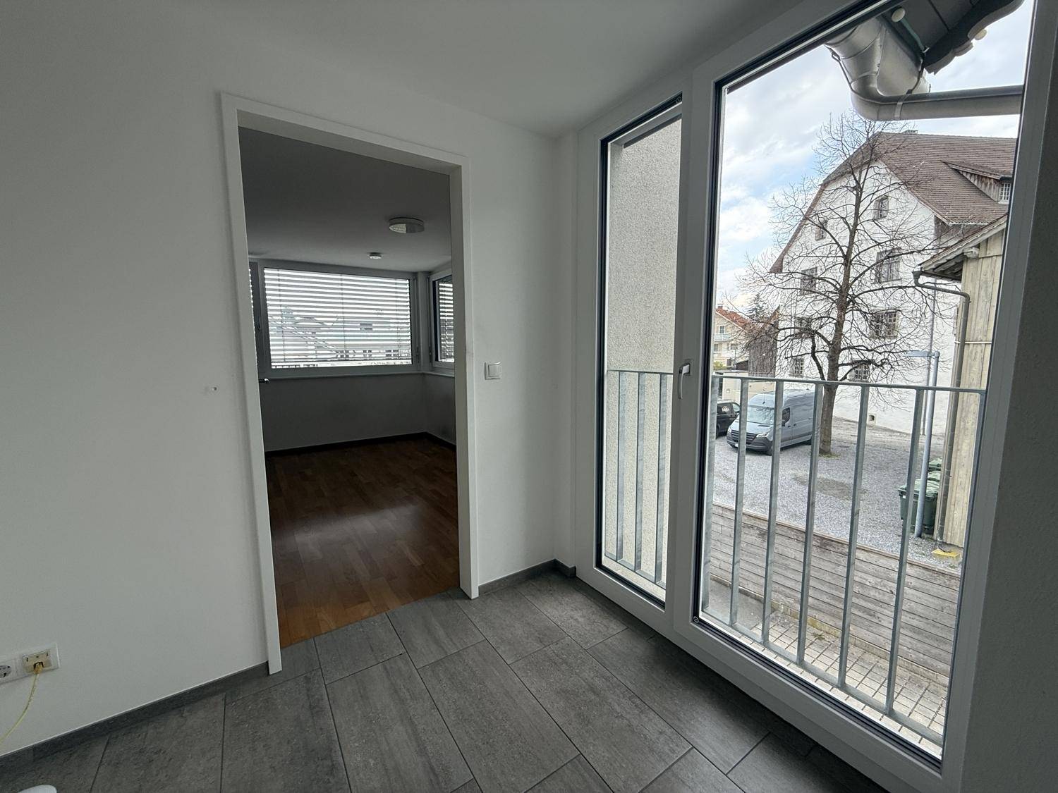 Heller Flurbereich mit Fliesenboden und französischem Balkon, der einen Blick auf die Straße bietet.