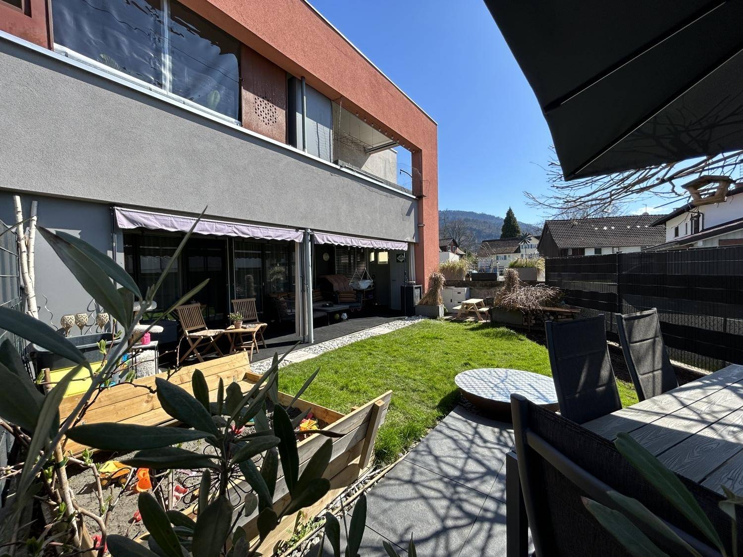 Gepflegter Garten mit Terrasse, Gartenmöbeln und Blick auf die umliegende Landschaft.