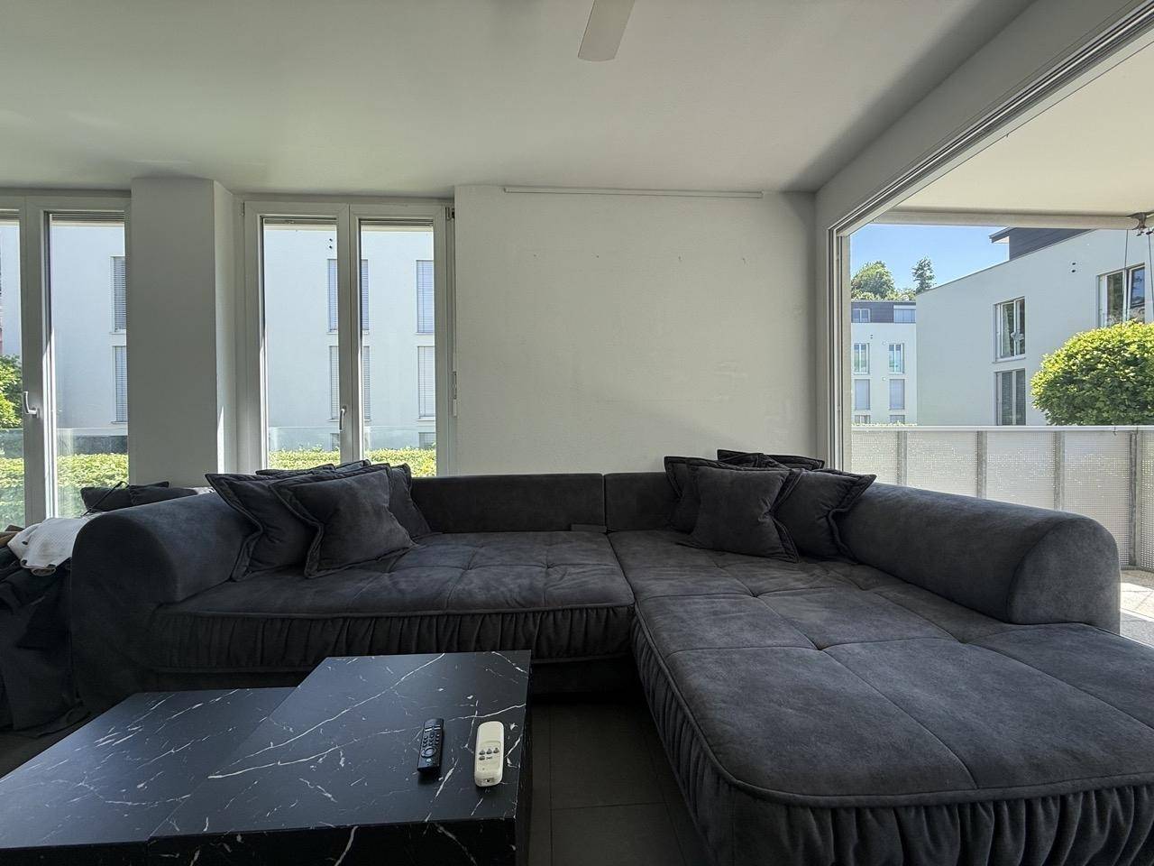 Gemütlicher Wohnbereich mit großem, bequemen Sofa und modernem Couchtisch in dunklem Marmor-Look.