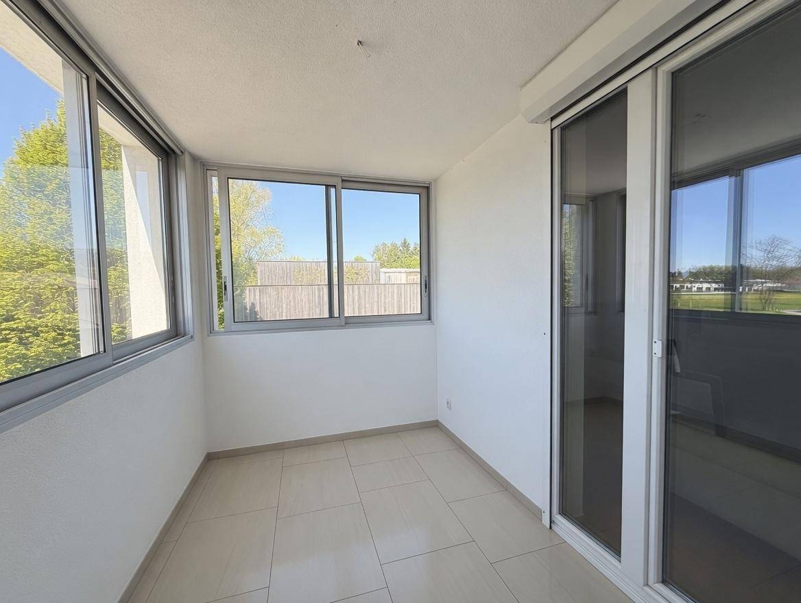 Verglaster Balkon mit Fliesenboden und weitem Blick ins Grüne, ideal für entspannte Stunden.