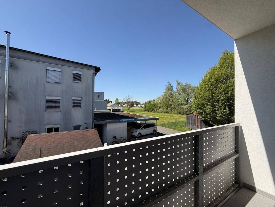 Balkon mit modernem Metallgeländer und weitem Blick auf die umliegende Landschaft und Nachbargebäude.