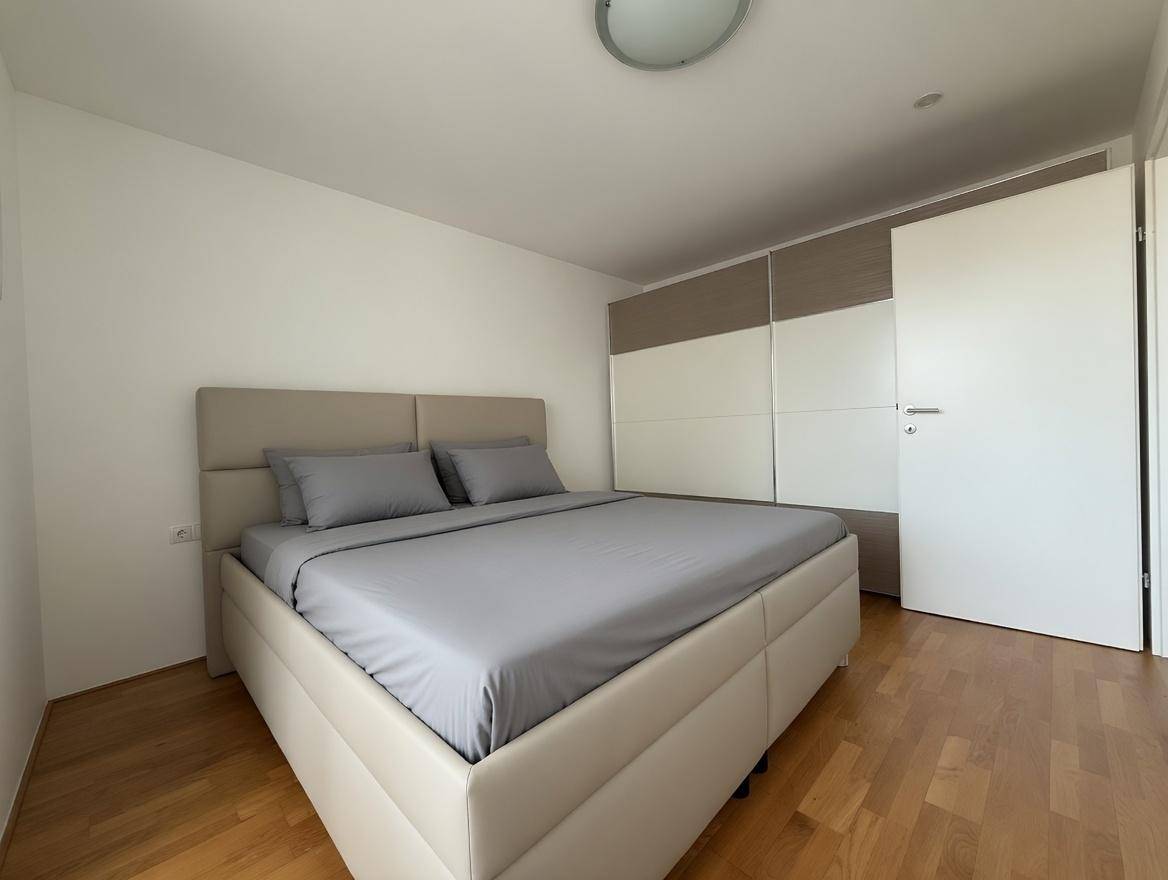 Helles Schlafzimmer mit Doppelbett, Holzboden und integriertem Kleiderschrank, modern eingerichtet.