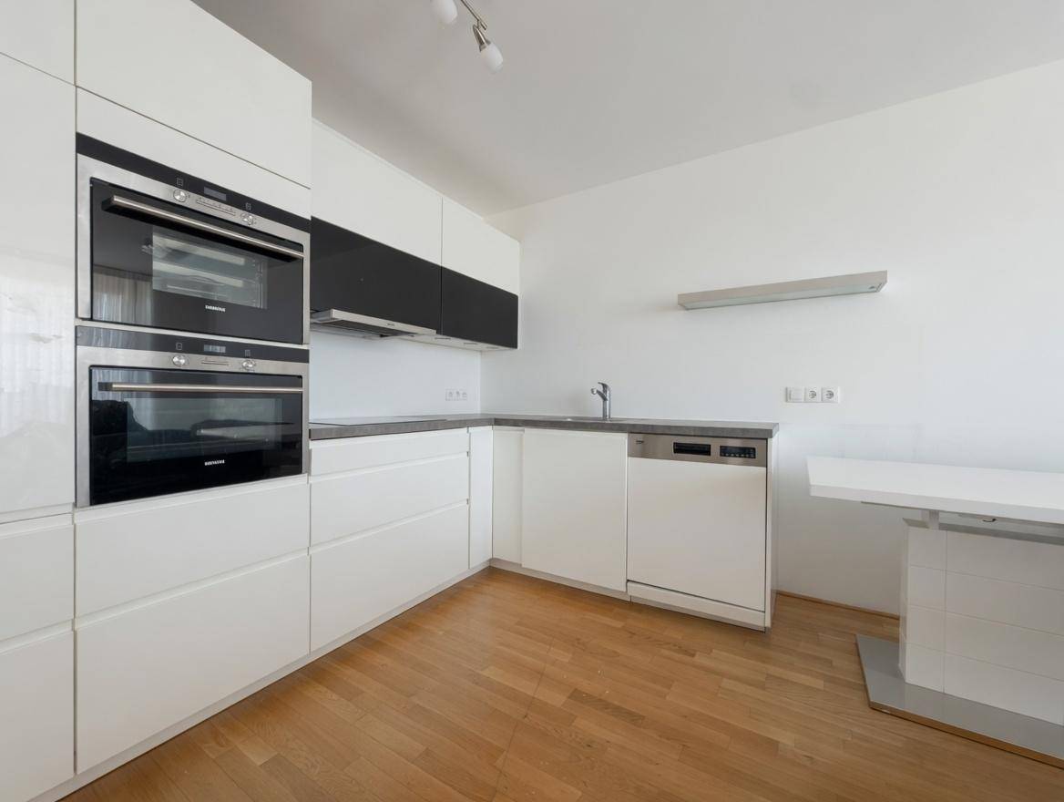 Moderne Einbauküche mit weißen Hochglanzfronten, integrierten Siemens-Geräten und Holzboden.