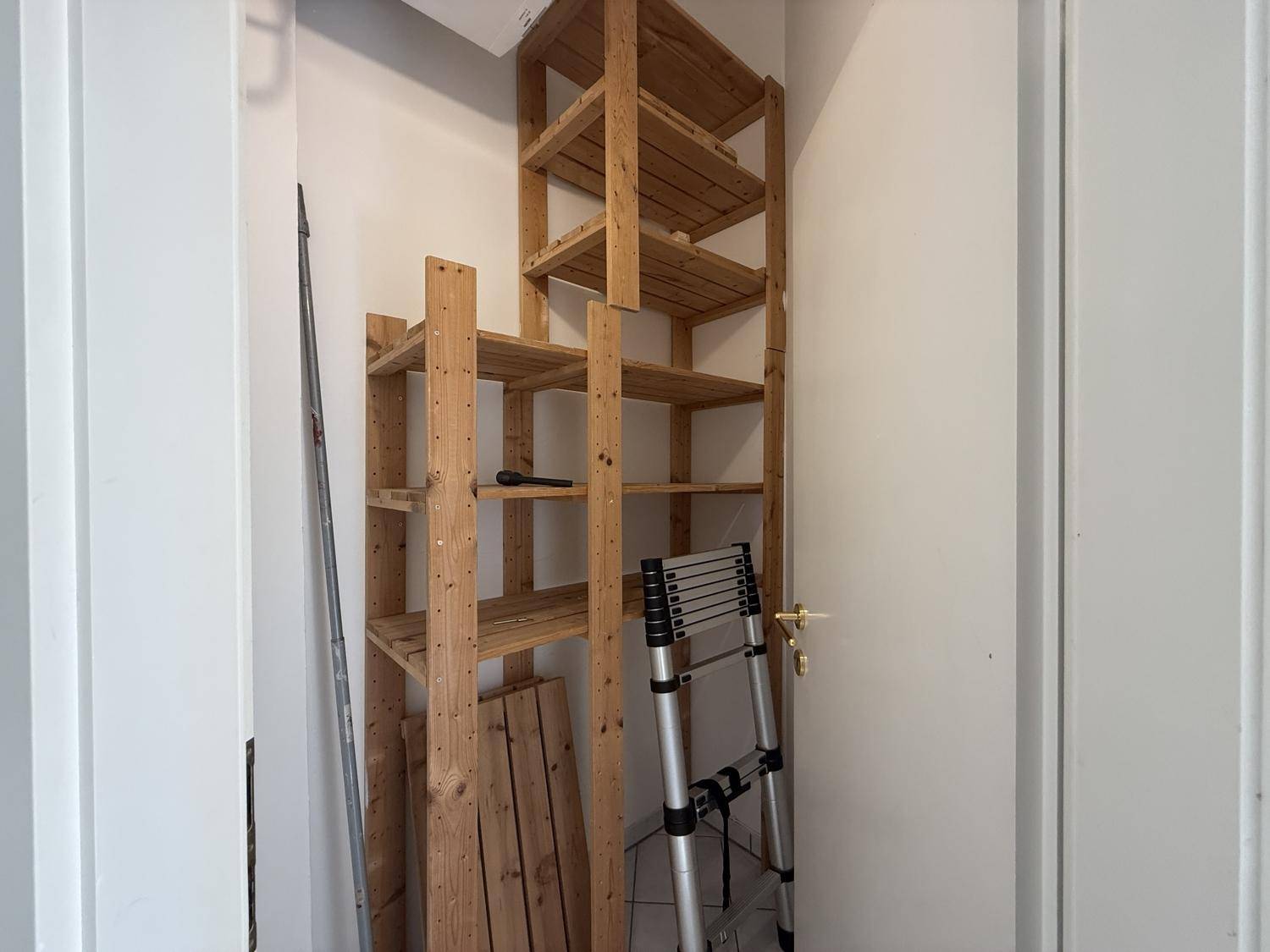 Praktischer Abstellraum mit Holzregalen für zusätzlichen Stauraum und Ordnung.
