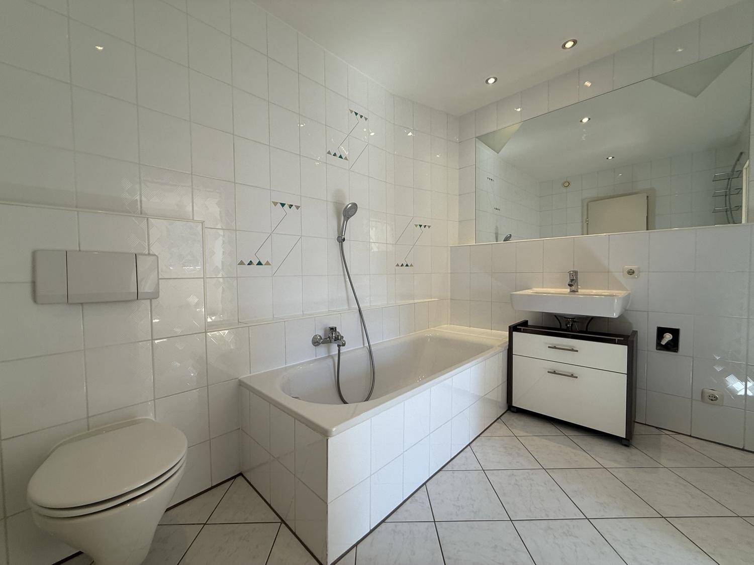 Geräumiges Badezimmer mit Badewanne, WC und Waschbecken mit Spiegelschrank.