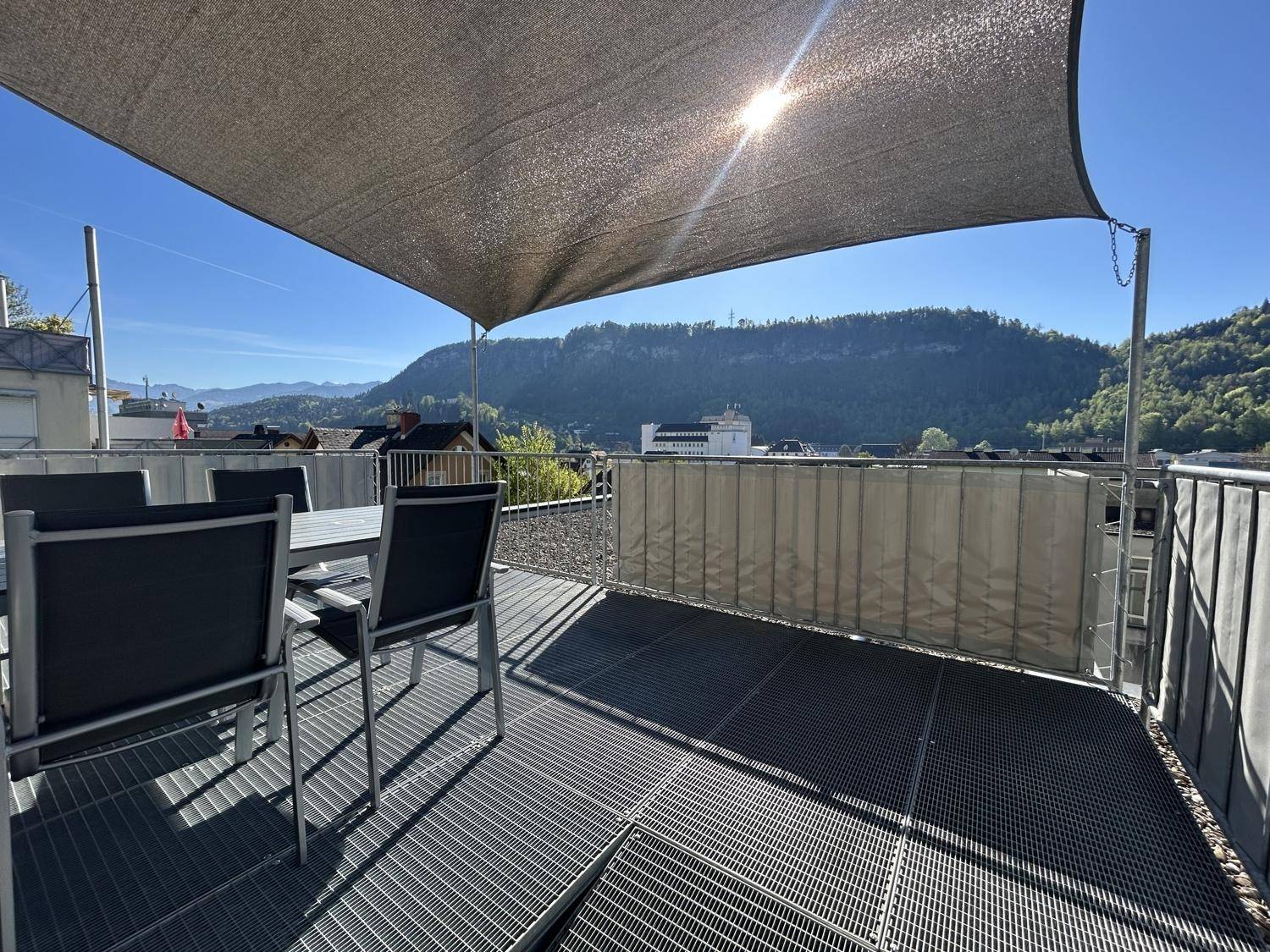 Geräumige Dachterrasse mit modernen Gartenmöbeln, Sonnensegel und weitem Blick auf die grüne Berglandschaft.