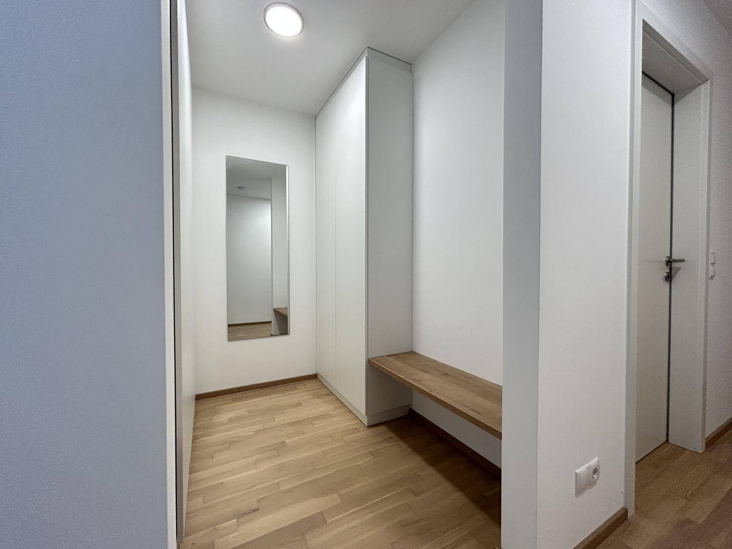 Eingangsbereich mit integriertem Kleiderschrank, Sitzbank und Spiegel, ausgestattet mit Parkettboden.