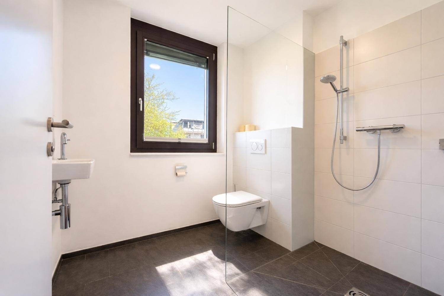 Modernes Badezimmer mit ebenerdiger Dusche, Wand-WC und Fenster für Tageslicht.